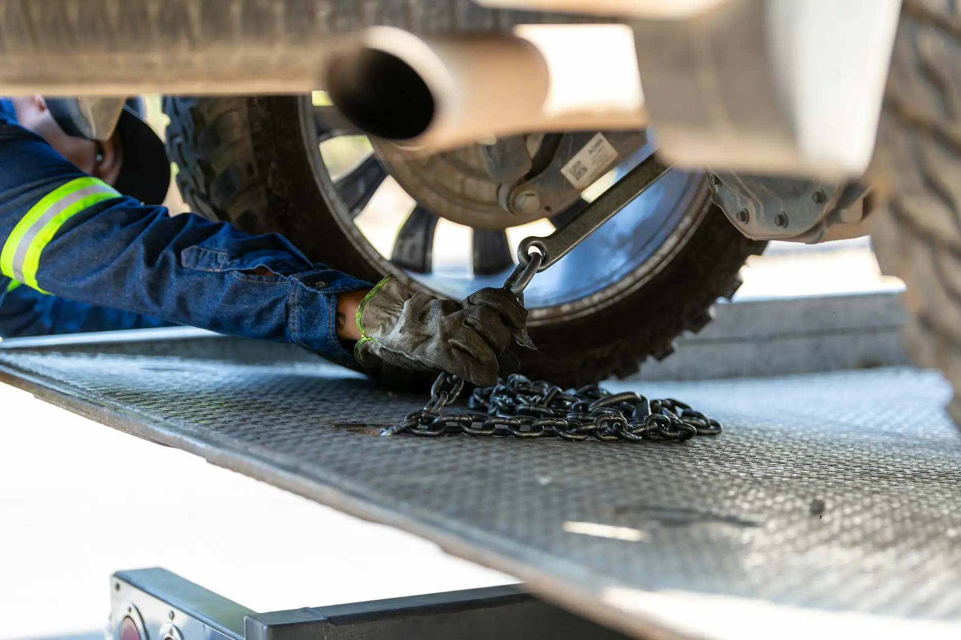 A close-up of a tow truck operator securing a vehicle's tire to a flatbed using heavy-duty straps in Massillon, Ohio.